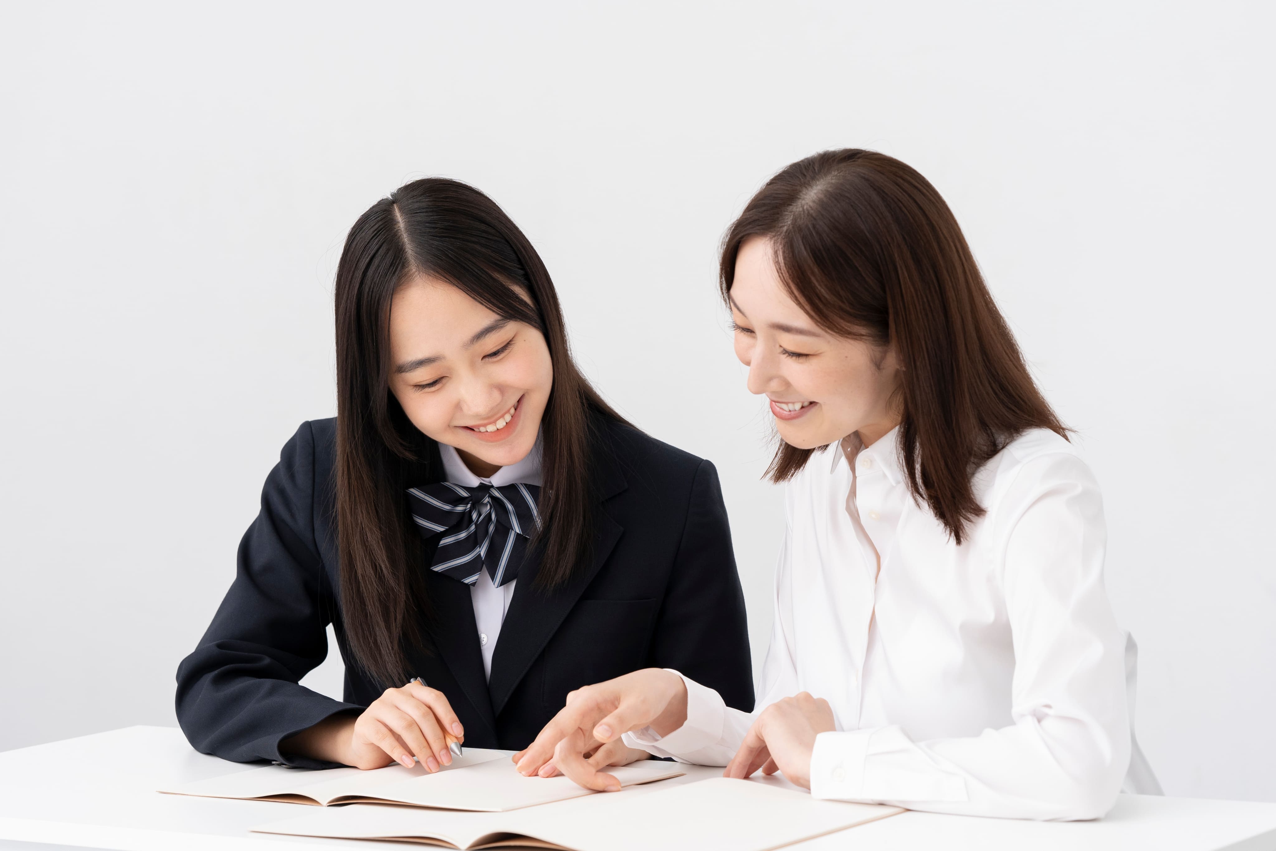 学生が女性講師に勉強を教えてもらっている様子